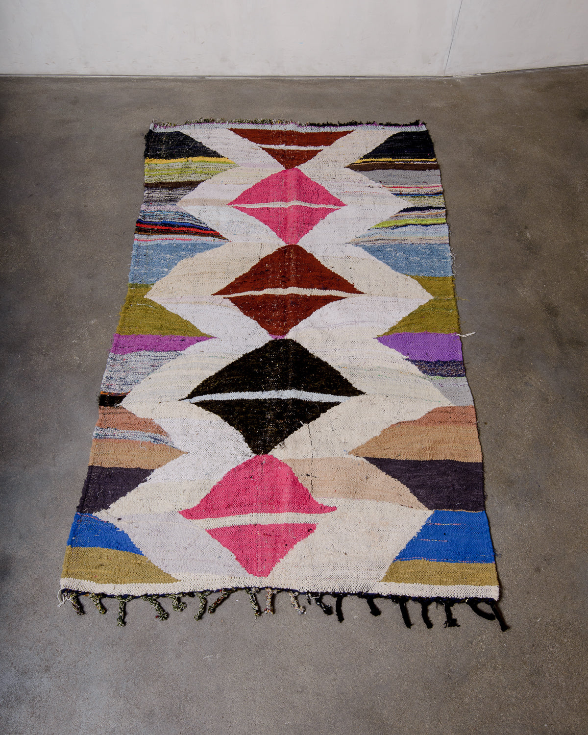 Berberlin vintage kelim rug made of recycled materials laying flat on a concrete floor.